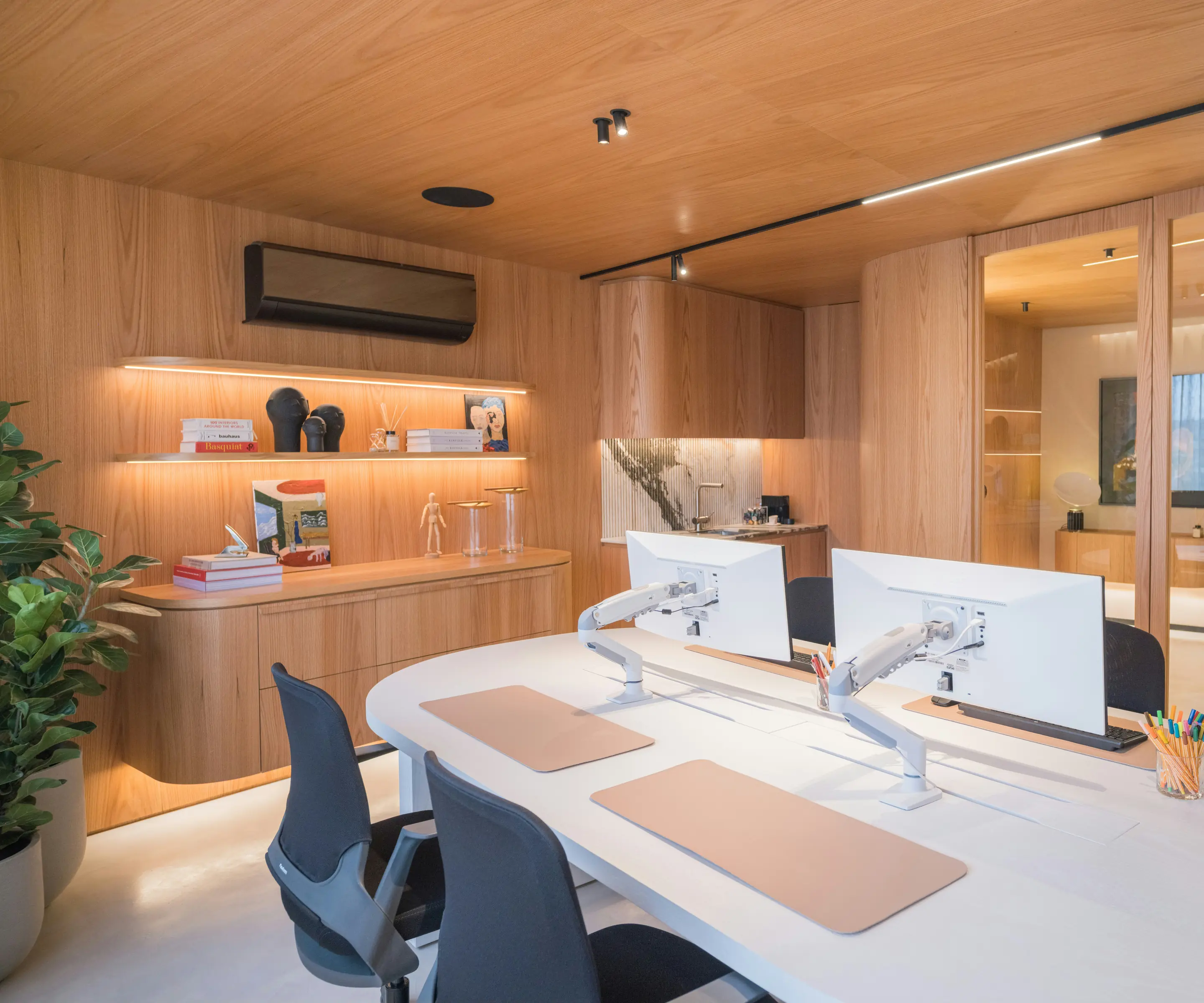 Workstations with monitors in an office lined with warm oak millwork